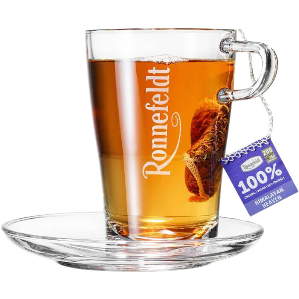 Ronnefeldt Premium Teebeutel Himalayan Heaven in Glastasse mit bernsteinfarbenem Tee und Glasuntertasse