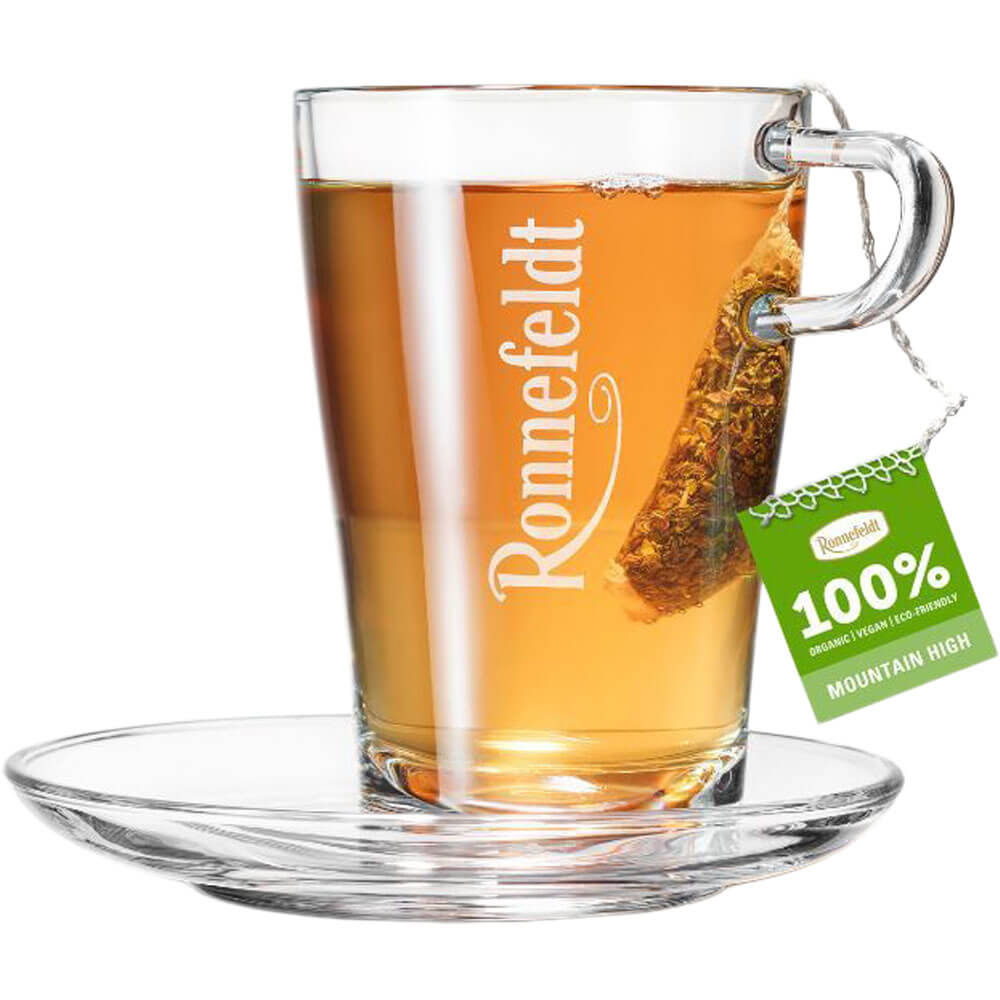 Ronnefeldt Premium Teebeutel Mountain High in Glastasse mit goldbraunem Tee und Glasuntertasse