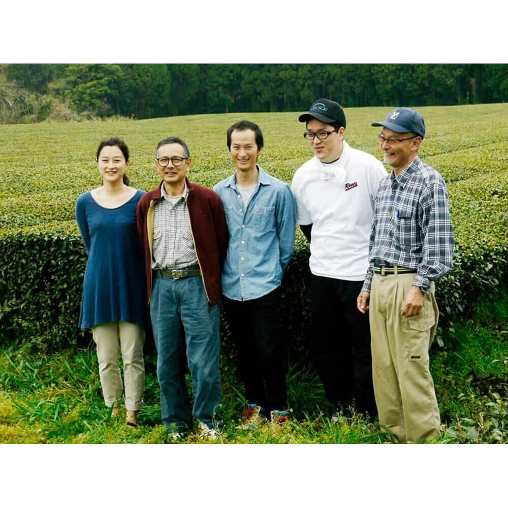 Japanische Familienaufstellung im Kirishima-Teefeld – Mitglieder der Hayashi-Teefamilie in natürlicher Umgebung, symbolisch für Herkunft und Tradition#variante_30g